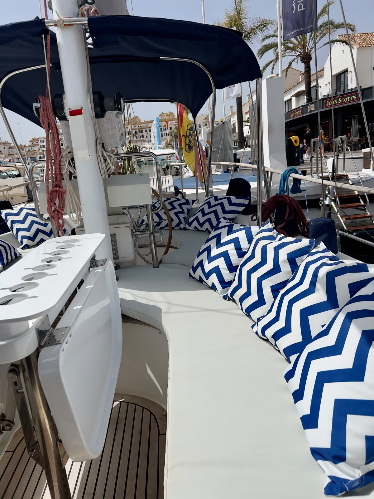 Bañera con cojines azules y timón de madera en Puerto Banús